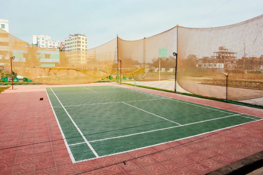 Bright outdoor tennis court with netting surrounded by urban buildings, offering a unique sports setting.